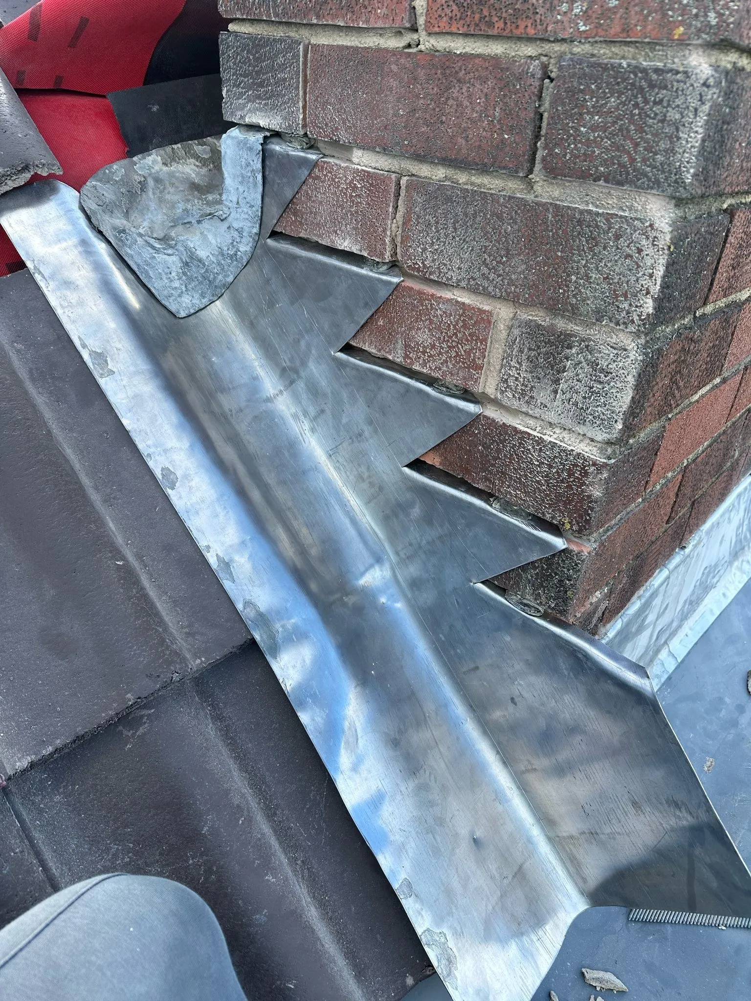 Lead back gutter and step flashing dressed around a brick chimney