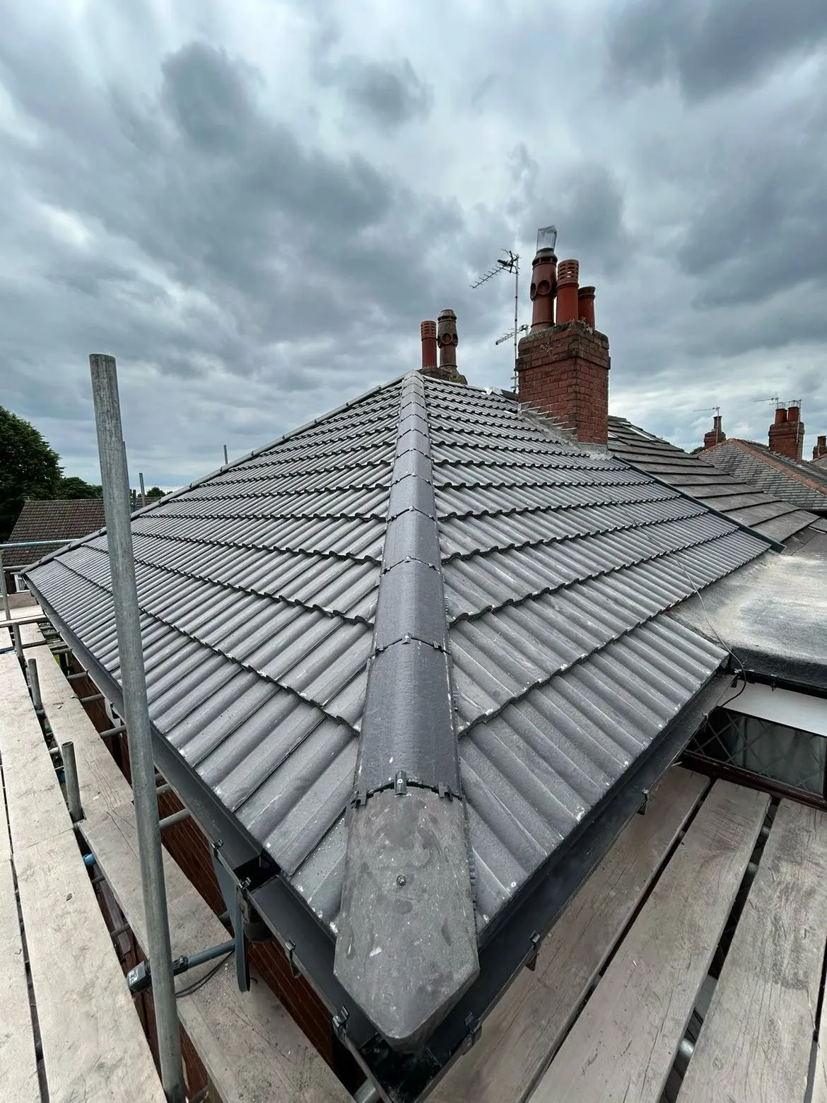 Concrete tile hip roof with two repointed chimney stacks