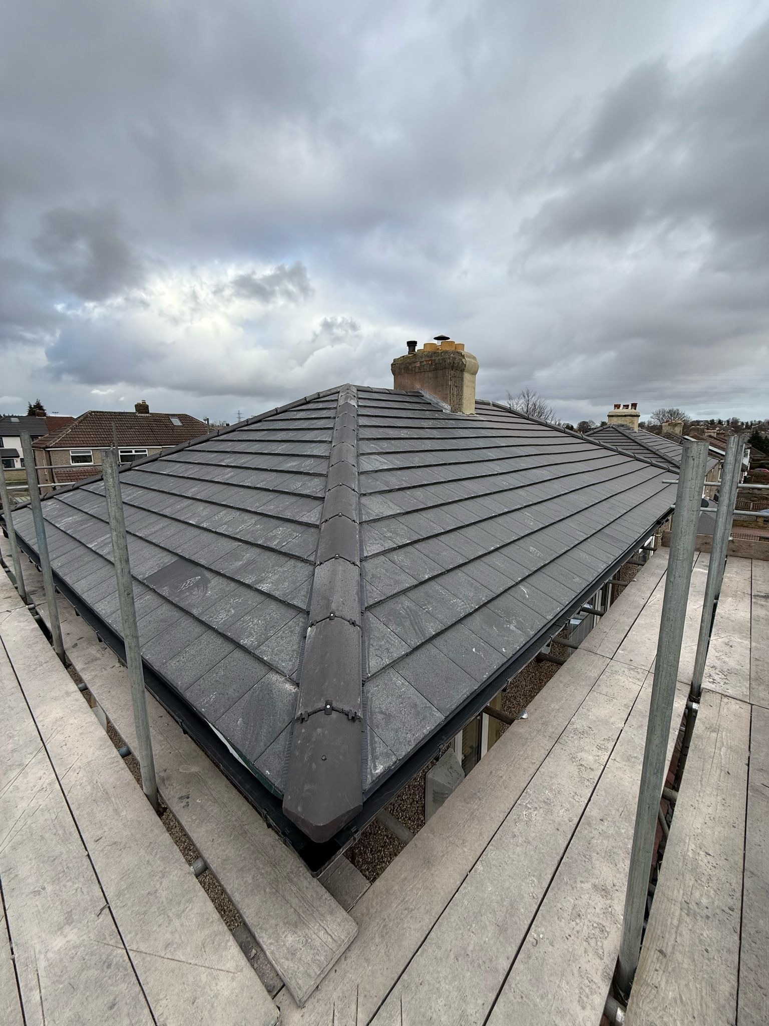 Re-roofed hip roof after storm damage, with scaffold still in place