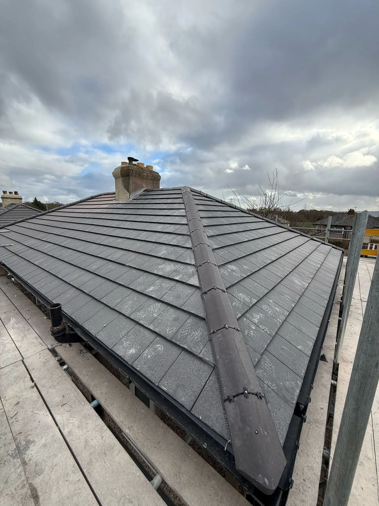 Hip roof re-covered in slate-effect tiles under a dramatic Yorkshire sky