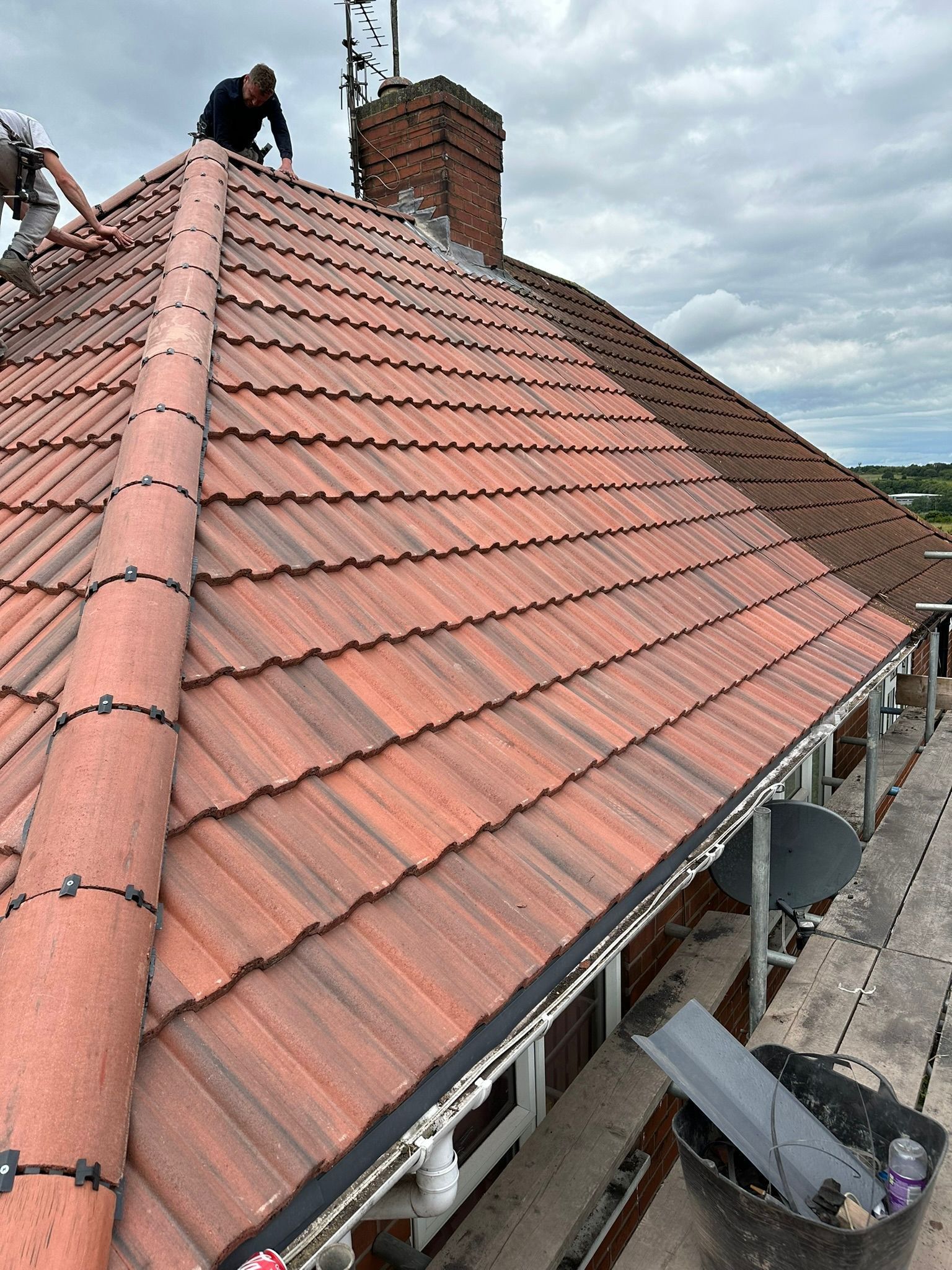 Two Oakwell roofers finishing a terracotta tile roof
